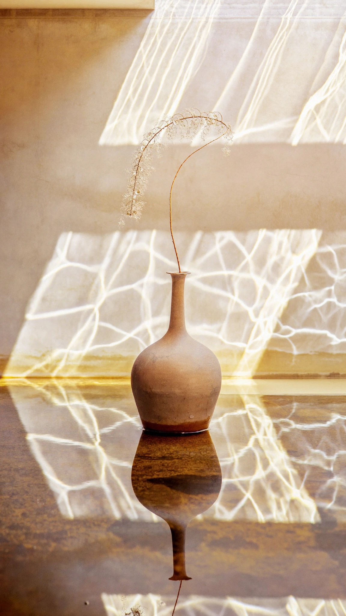 Grand vase en terracotta posé dans une flaque reflétant la lumière naturelle